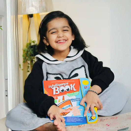 Child holding an 'intelligence Book' and smiling indoors